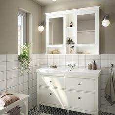 a white bathroom with black and white floor tiles on the walls, two mirrors above the sink