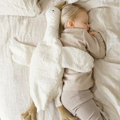 a baby sleeping on a bed with a stuffed animal