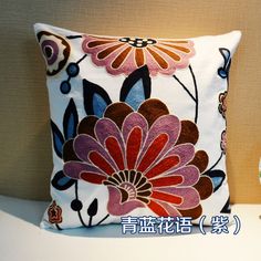 a decorative pillow with flowers on it sitting on a shelf next to a small vase