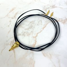 A versatile golden raven bird skull wrap choker! You can wear this super long suede choker in tons of different ways. As a necklace: one round around your neck, leaving the little charms hanging, or two rounds and a knot. As a hair accessory, for an original touch.  As a bracelet, around your wrist. As a belt... So many possibilities! Let your imagination work! I make my suede chokers super long (1 m 20 / 47 in) to let you express your creativity with them. Like all my jewelry, this choker carries deep symbols. This necklace is embellished with a bird skull who adds a dark vibe to this choker. Two feathers adorn the ends of the choker. Made with nickel-free and lead-free metal, and vegan leather, this accessory will complete a witchy, goth, steampunk, or rock style. Care instructions: To k Deep Symbols, Golden Choker, Raven Bird, Wrap Necklace, Bird Skull, Wrap Necklaces, Necklace Black, Multi Strand Necklace, Strand Necklace