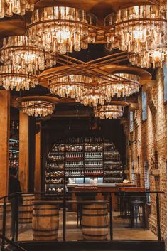 a wine shop with chandeliers hanging from the ceiling and wooden barrels in front of it