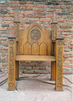 an old wooden bench sitting in front of a brick wall with carvings on the back