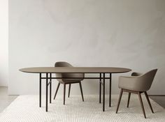 an oval table with two chairs next to it on a white carpeted floor in front of a gray wall