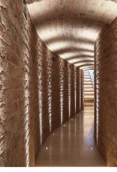 a long hallway with brick walls and steps leading up to the top floor in an indoor area