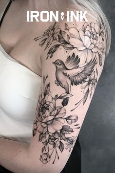 a woman's arm with flowers and a bird tattoo on her left shoulder, which reads iron & ink