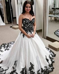 a woman standing in front of a mirror wearing a black and white dress with flowers on it