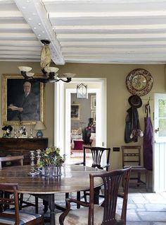 the dining room table is surrounded by chairs and an old man painting on the wall