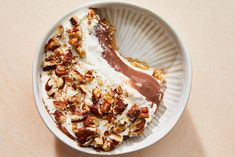 a white bowl filled with yogurt and nuts on top of a pink table