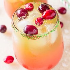 two glasses filled with drinks and garnished with cranberries on the rim