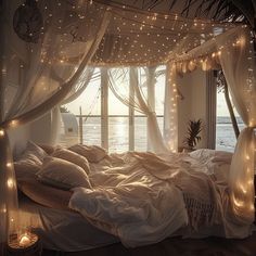 an unmade bed with lights hanging from the ceiling and curtains on the windowsill