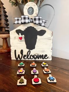 a wooden welcome sign sitting on top of a table next to some small magnets