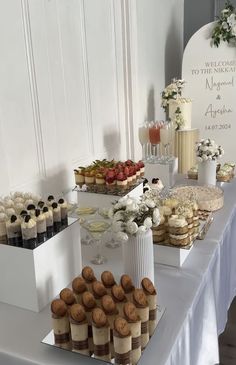 a table topped with lots of desserts and pastries next to a white wall