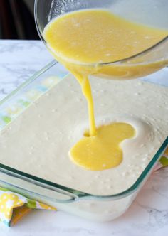 someone pouring orange juice into a glass bowl