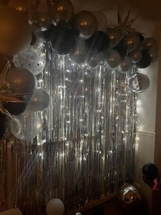 balloons and streamers hanging from the ceiling in front of a mirror wall at a party