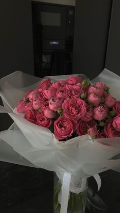 a bouquet of pink roses wrapped in white paper