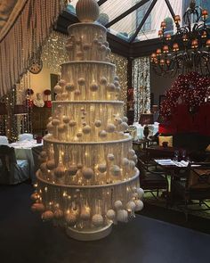 a christmas tree made out of plastic balls in a room filled with tables and chairs