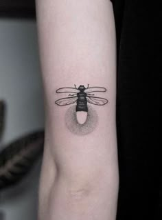 a black and white photo of a bee tattoo on the left inner arm, with an insect in it's center