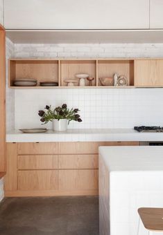 a kitchen with wooden cabinets and white counter tops, along with a plant in a vase