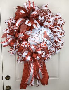 a red and white wreath with cardinals on it hanging on the front door for christmas