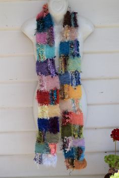 a multicolored scarf hanging from the side of a wall next to a potted plant