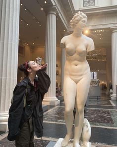 a woman standing next to a white statue