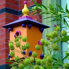 a colorful birdhouse with flowers in front of a brick building