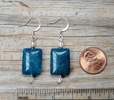 These stunning blue earrings are made with Apatite rectangular beads, fire polished Czech glass AB accent beads and pewter spacers.   The Apatite beads are 0.65 inches long, 0.55 inches wide, and 0.15 inches thick.  The earrings are available with silver or gold findings:  we make them with either gold or silver color pewter spacers and gold or silver plated headpins. The earwires on the earrings as pictured are silver plated brass hooks, nickel free and hypoallergenic for sensitive ears.  Addit Nickel-free Rectangular Czech Glass Jewelry, Blue Rectangular Earrings With Ear Wire, Blue Rectangular Earrings, Rectangular Earrings, Brass Hooks, Brass Hook, Head Pins, Blue Earrings, Sensitive Ears