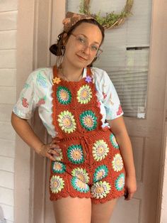 a woman standing in front of a door wearing an orange crocheted granny's outfit