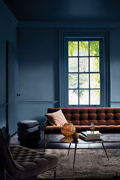 a living room with blue walls and furniture in the corner, including a brown couch