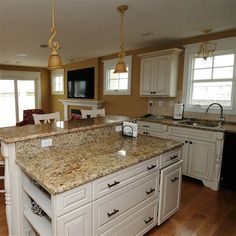 a large kitchen with an island in the middle and two lights hanging from the ceiling