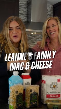 two women standing next to each other with mac and cheese on the counter in front of them