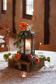 a lantern with flowers and candles on a table