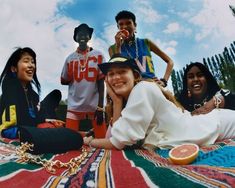 a group of young people sitting on top of a colorful blanket