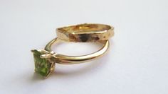 "Stunning set of 2 14K yellow gold stacking rings - a peridot solitaire ring and a unique wedding band. This set consists of 2 beautiful solid gold rings: The 1st is a rustic wedding band, with an uneven design that gives it a distinctive \"handmade\" look. It is forever changing, never looking the same. The 2nd ring has a sparkling green rectangular peridot set in a beautiful base. This can be an awesome engagement ring. This modern bridal ring set is perfect for a boho bride. The rings have a Wedding Ring Set Gold, Gold Peridot Ring, Women Gold Ring, Yellow Gold Stacking Rings, Gold Ring Women, Rustic Wedding Bands, Rings Solitaire, Wedding Band Women, Ring Wedding Band