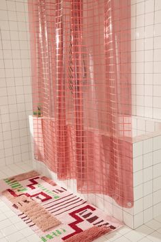 a pink shower curtain in a bathroom next to a rug