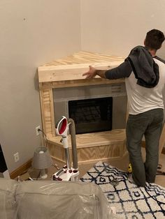 a man standing next to a microwave oven on top of a wooden table in a living room