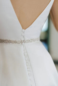 the back of a woman's white dress with beaded trimmings on it