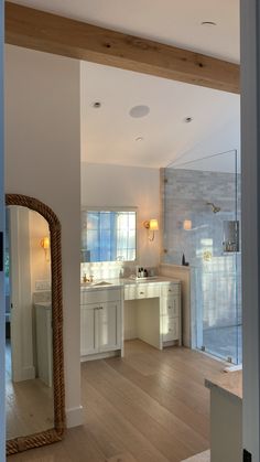 a large bathroom with wooden floors and white cabinets