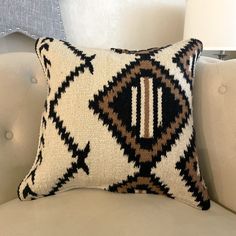 a white couch with a black and brown pillow on it's backrest, next to a lamp