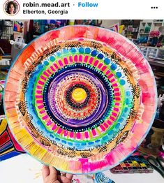 a person holding up a colorful paper plate