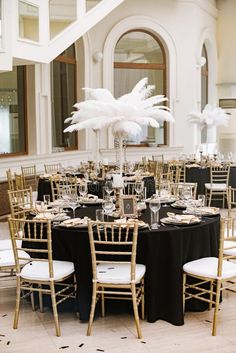 the tables are set up for an event with black and white linens, gold chairs and tall centerpieces - stock image