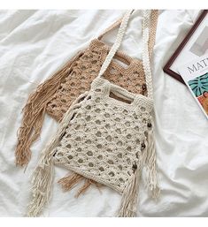 two crocheted purses sitting on top of a bed next to a book