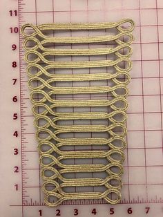 a piece of metal wire sitting on top of a ruler