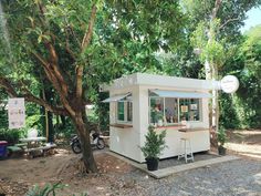 a small white building sitting next to a tree