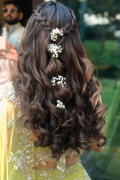 the back of a woman's head with long hair and flowers in her hair