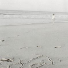 someone is walking on the beach with their name written in the sand and there are footprints