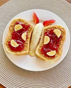 two pieces of bread with bananas and strawberry jam on them sitting on a white plate