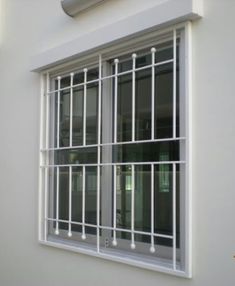 a window with bars on the side of it next to a white wall and light fixture