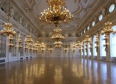 an empty ballroom with chandeliers and windows in the ceiling is lit by golden lights