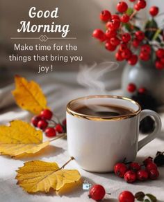 a cup of coffee sitting on top of a table next to autumn leaves and berries